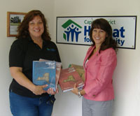 Dorothy Harris presents books to manager of Habitat for Humanity.